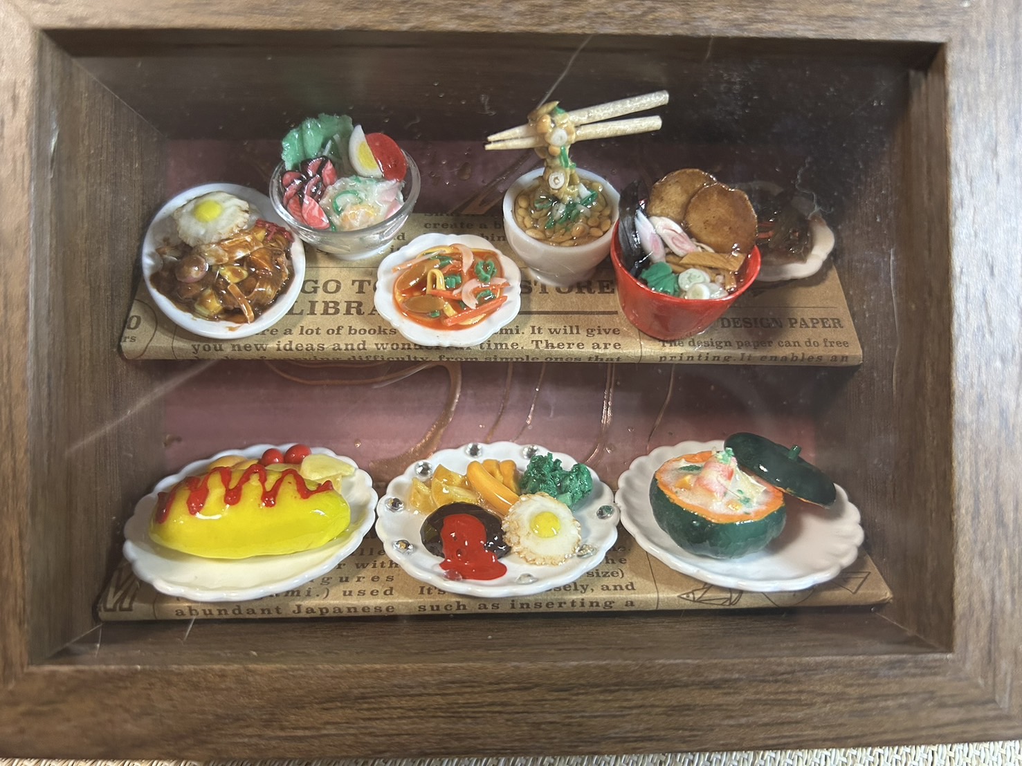 二段の木製スタンドに並んだ、ミニチュアのラーメンやオムライスなどのごちそう