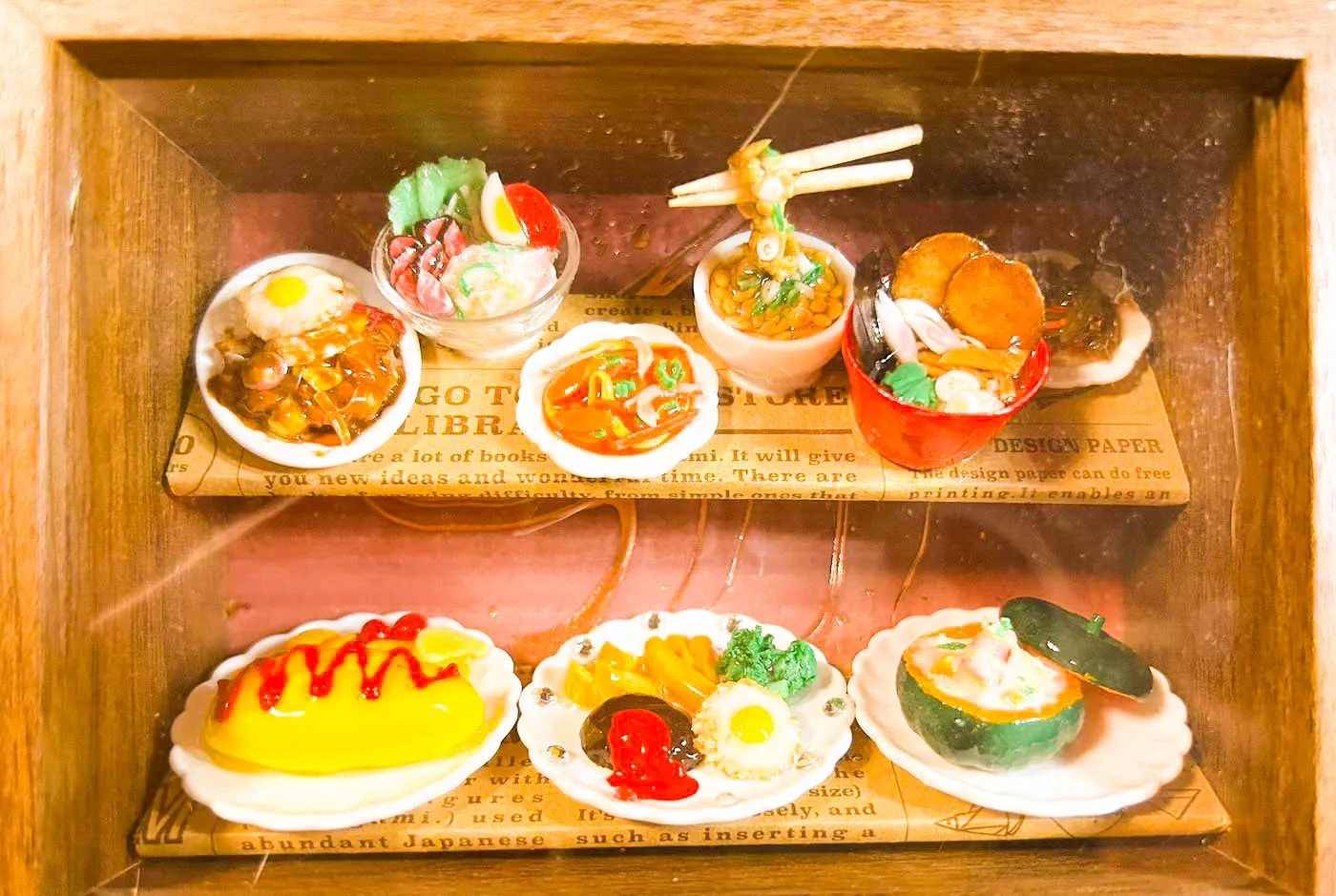 二段の木製スタンドに並んだ、ミニチュアのラーメンやオムライスなどのごちそう